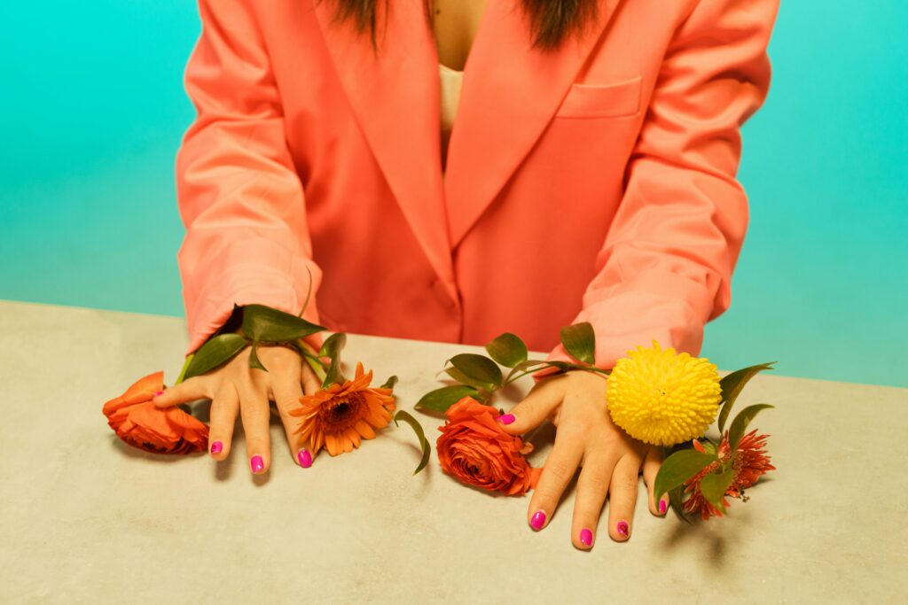 Close-up of hands on colorful flowers against a bright background.